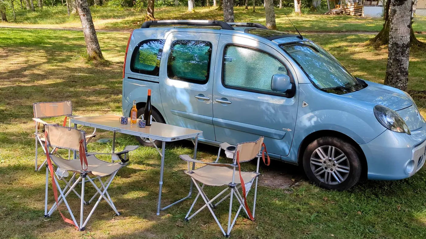 Kangoo aménagé au camping avec table et chaises pliantes