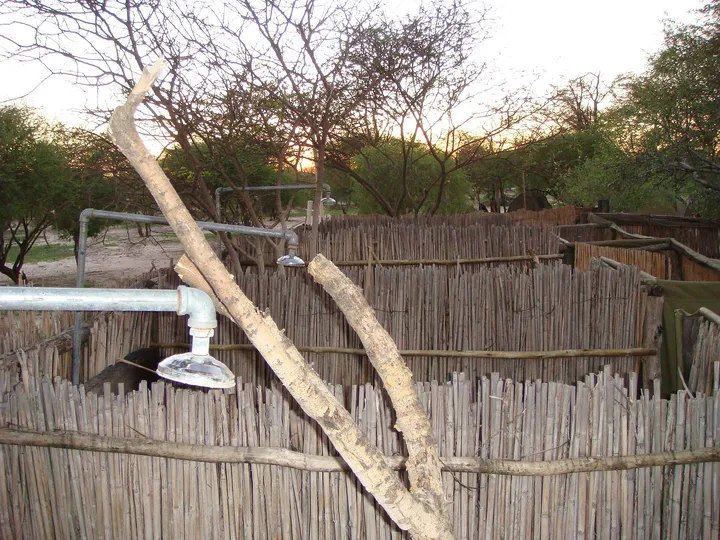 Douche extérieure rustique dans un enclos de branchages